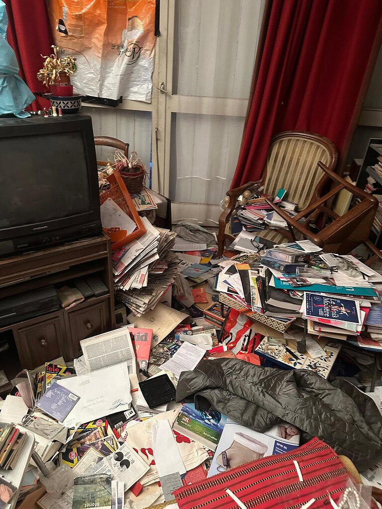 Désordre et débris dans un salon avec meubles et vieux appareils électroniques.